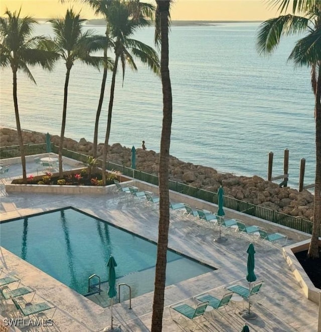 pool at dusk featuring a water view