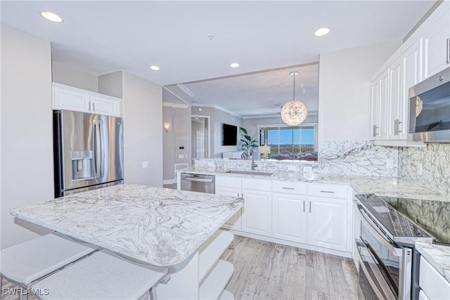 kitchen with white cabinetry, appliances with stainless steel finishes, sink, and a kitchen breakfast bar