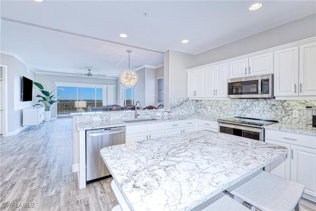 kitchen with white cabinetry, sink, a kitchen breakfast bar, kitchen peninsula, and stainless steel appliances