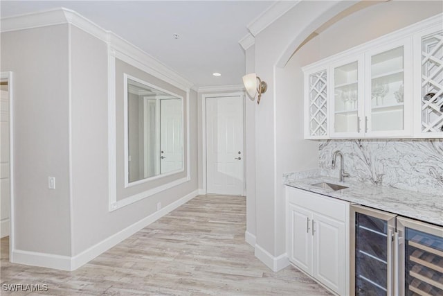 bar with sink, beverage cooler, light stone countertops, decorative backsplash, and white cabinets