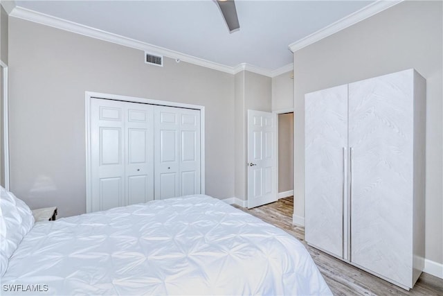 bedroom featuring ornamental molding, ceiling fan, light hardwood / wood-style floors, and a closet