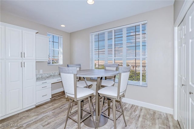 dining area with built in desk and light hardwood / wood-style flooring