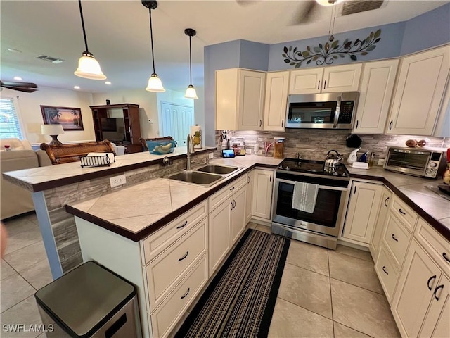 kitchen featuring pendant lighting, sink, backsplash, ceiling fan, and stainless steel appliances