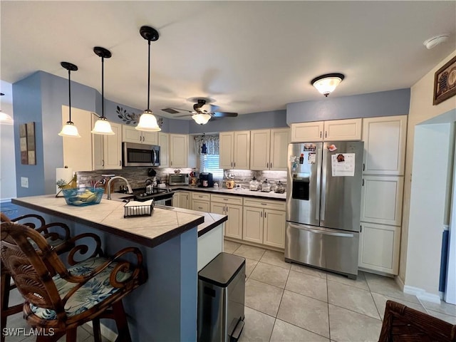 kitchen with appliances with stainless steel finishes, pendant lighting, sink, decorative backsplash, and kitchen peninsula