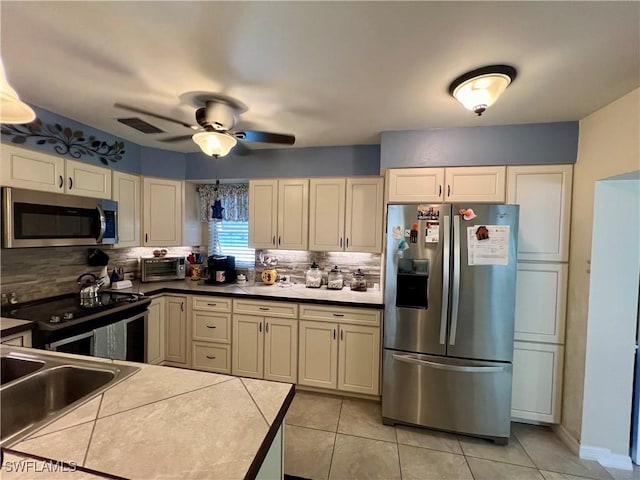 kitchen with backsplash, tile counters, light tile patterned floors, ceiling fan, and stainless steel appliances