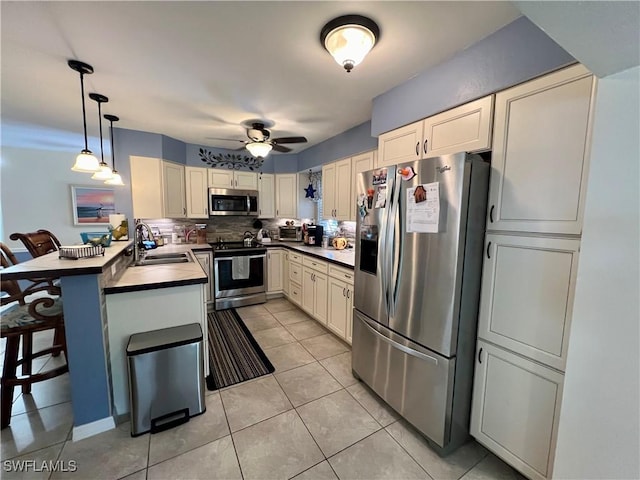 kitchen with sink, appliances with stainless steel finishes, hanging light fixtures, a kitchen breakfast bar, and kitchen peninsula