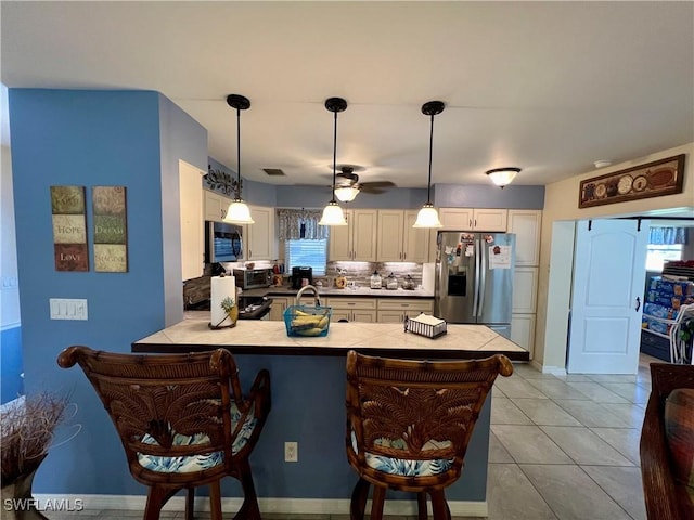 kitchen with light tile patterned flooring, decorative light fixtures, a kitchen breakfast bar, kitchen peninsula, and stainless steel appliances