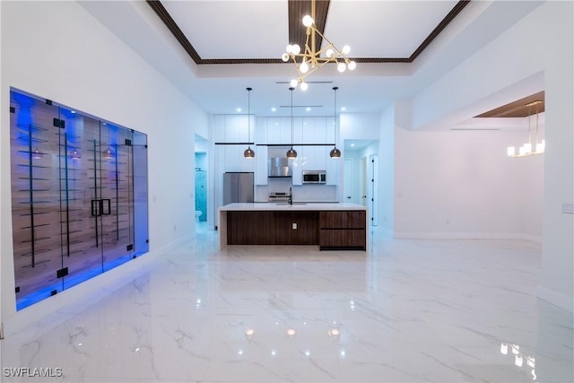 kitchen with pendant lighting, a chandelier, a large island with sink, ornamental molding, and stainless steel appliances