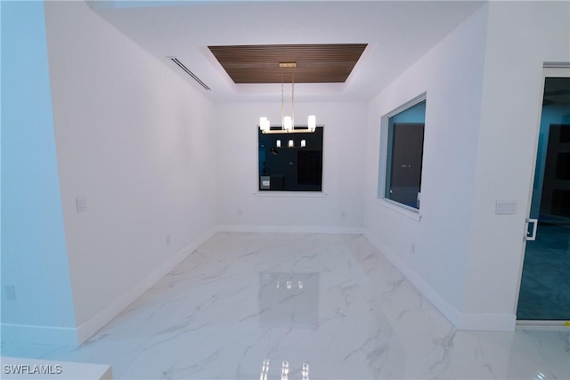 interior space with a raised ceiling and a notable chandelier