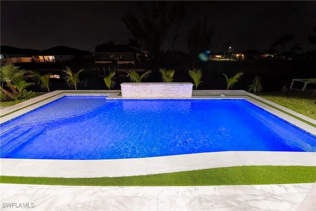 view of pool at twilight