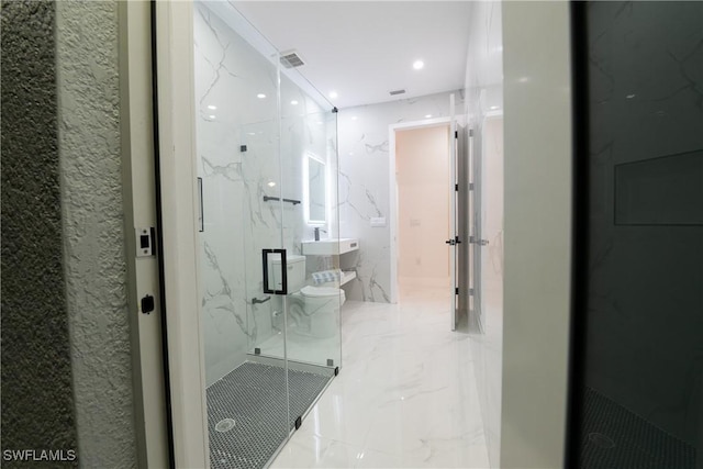 bathroom with a shower with door and toilet