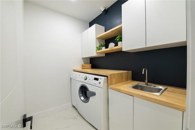 clothes washing area featuring separate washer and dryer, sink, and cabinets