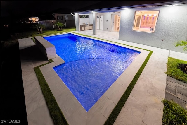 pool at night with a patio area