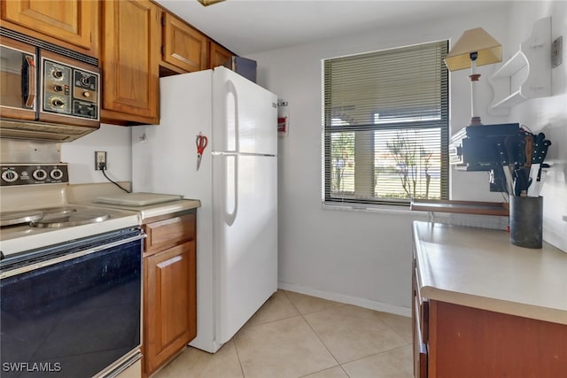 kitchen with pendant lighting, light tile patterned floors, range with electric stovetop, and white fridge