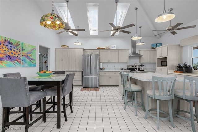 kitchen with wall chimney exhaust hood, stainless steel appliances, decorative light fixtures, and a skylight