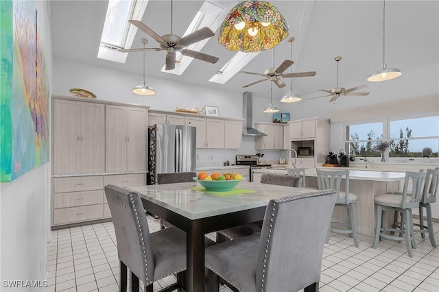 dining space featuring sink, a skylight, high vaulted ceiling, and light tile patterned floors