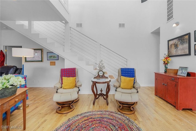 living area with a towering ceiling and light hardwood / wood-style floors