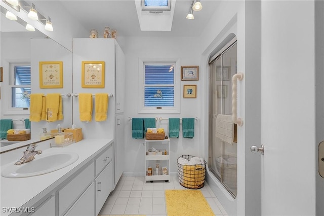 bathroom with a skylight, tile patterned floors, a shower with shower door, and vanity