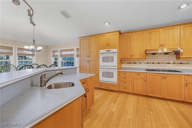 1538 Wilton Ln, Sanibel, FL 33957 - kitchen with white double oven, a chandelier, under cabinet range hood, a sink, and gas stovetop