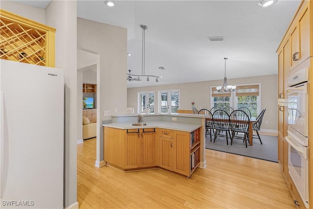 1538 Wilton Ln, Sanibel, FL 33957 - kitchen featuring light countertops, light wood-style flooring, a peninsula, and white appliances