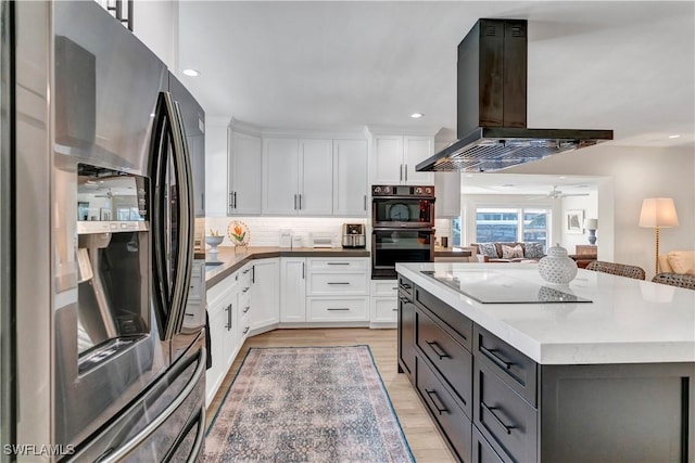 kitchen featuring white cabinets, decorative backsplash, island exhaust hood, black appliances, and light wood-type flooring