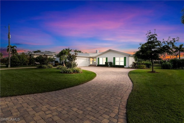 ranch-style house featuring a garage and a yard