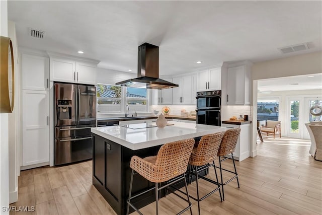 kitchen with white cabinetry, island exhaust hood, a kitchen island, and black appliances