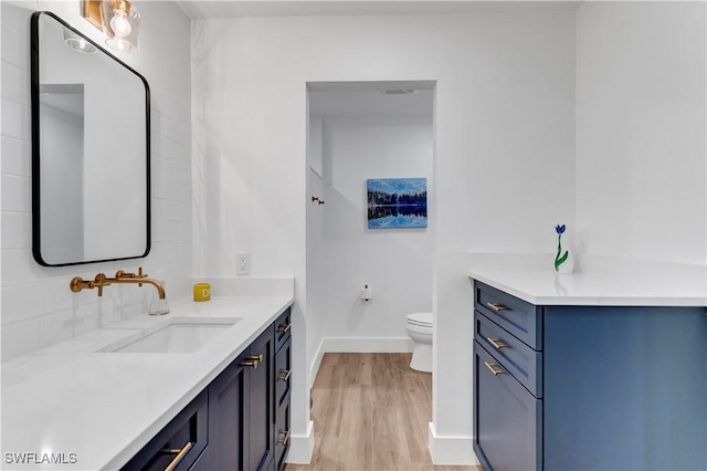 bathroom with hardwood / wood-style flooring, vanity, and toilet