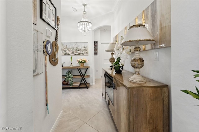 hall featuring light tile patterned flooring and a notable chandelier