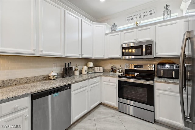 kitchen featuring white cabinetry, stainless steel appliances, light stone counters, ornamental molding, and decorative backsplash