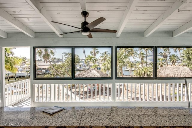 unfurnished sunroom with ceiling fan, wood ceiling, and beam ceiling