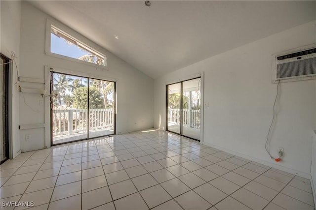 tiled spare room featuring a wall mounted AC and high vaulted ceiling