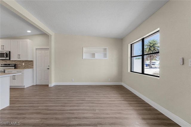 interior space featuring vaulted ceiling, light hardwood / wood-style floors, and a textured ceiling