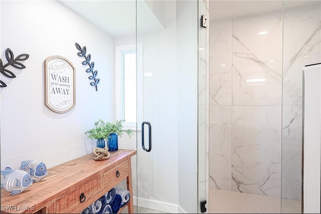 bathroom with a marble finish shower and baseboards