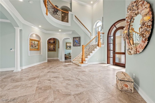 foyer entrance with ornamental molding, a high ceiling, and ornate columns