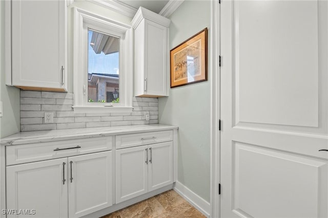 interior space with white cabinetry, backsplash, ornamental molding, and light stone countertops