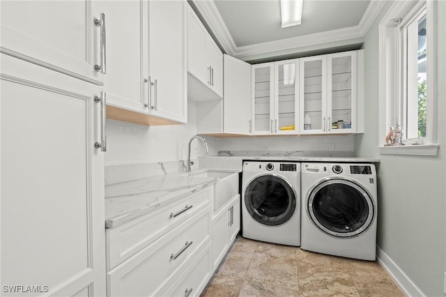 laundry room featuring sink, crown molding, washing machine and dryer, and cabinets