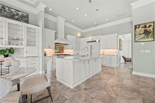 kitchen with pendant lighting, an island with sink, built in fridge, and white cabinets