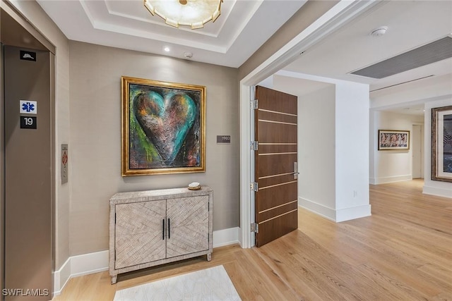 hall featuring a raised ceiling and light hardwood / wood-style flooring