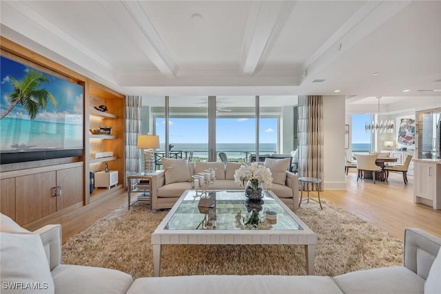 living room featuring built in features, an inviting chandelier, a water view, light hardwood / wood-style floors, and beamed ceiling