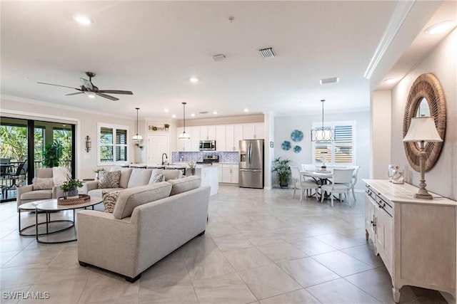 living room featuring light tile patterned floors, ceiling fan with notable chandelier, and ornamental molding