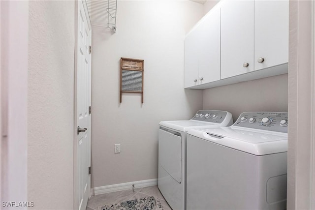 clothes washing area featuring cabinets and washer and clothes dryer