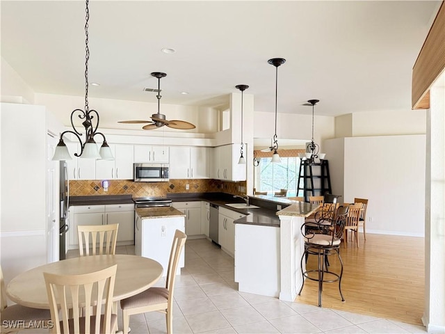 kitchen with white cabinetry, sink, decorative light fixtures, and stainless steel appliances