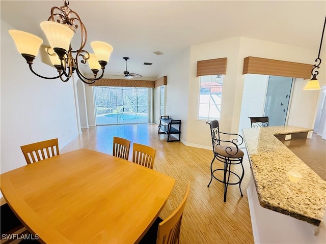 dining area with ceiling fan with notable chandelier and light hardwood / wood-style flooring