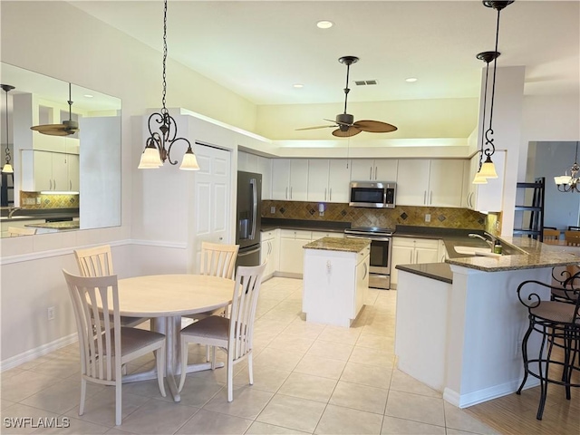 kitchen with sink, ceiling fan, stainless steel appliances, decorative light fixtures, and kitchen peninsula