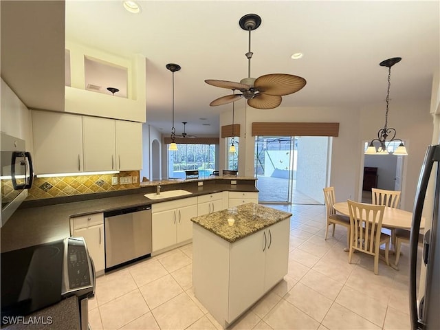 kitchen with sink, white cabinetry, appliances with stainless steel finishes, pendant lighting, and decorative backsplash