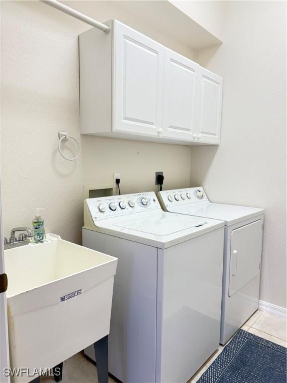 laundry room featuring sink, light tile patterned floors, cabinets, and independent washer and dryer