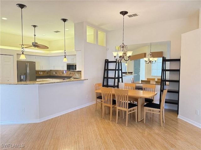 dining area featuring ceiling fan with notable chandelier and light hardwood / wood-style flooring