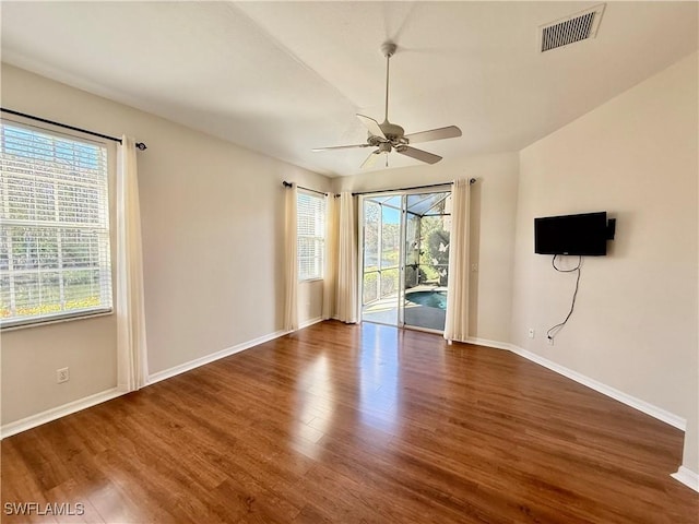 empty room featuring ceiling fan, dark hardwood / wood-style floors, and a wealth of natural light