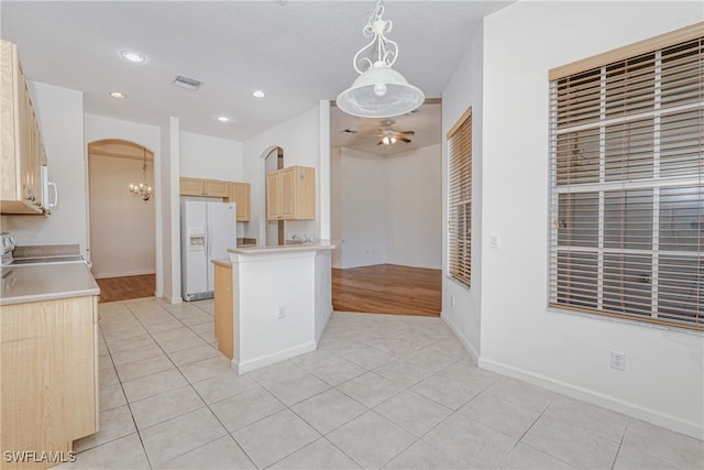 kitchen featuring pendant lighting, ceiling fan, white refrigerator with ice dispenser, and light tile patterned floors